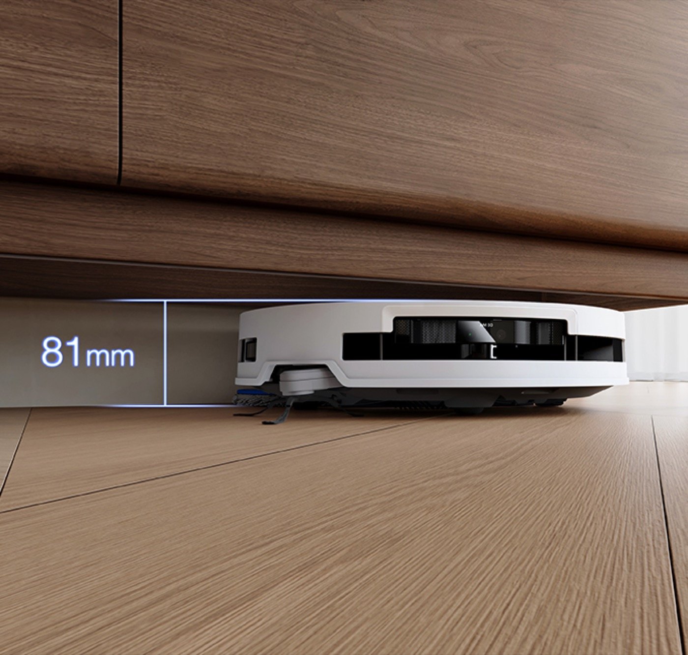 White robot vacuum sliding under a low wooden cabinet with an 81 mm height callout from the manufacturer