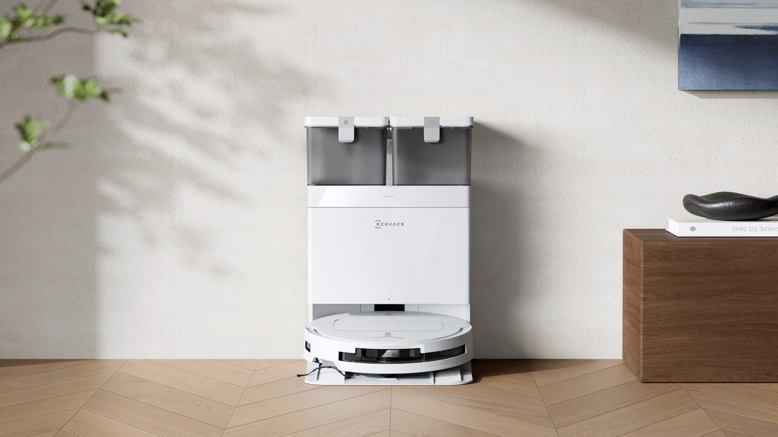 White ECOVACS DEEBOT T50 PRO OMNI docked in its white OMNI station on herringbone wood flooring, manufacturer photo